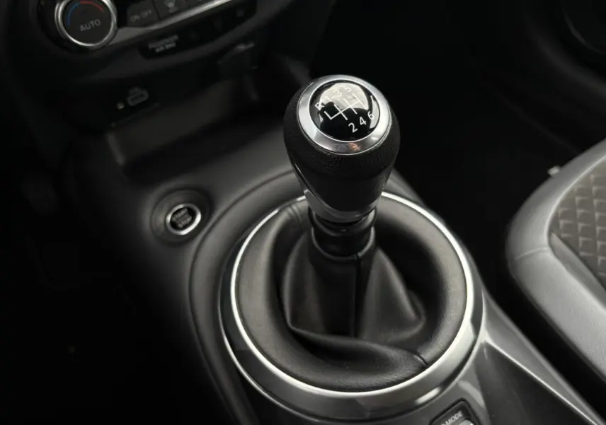 Le levier de vitesses manuel noir du Nissan Juke 2024, avec console centrale et siège partiel gris visible.