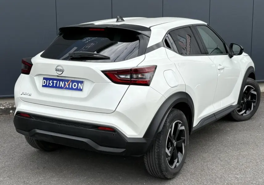 Nissan Juke blanc perle vu en 3/4 arrière droit, avec jantes alliage noires et vitres arrière teintées.