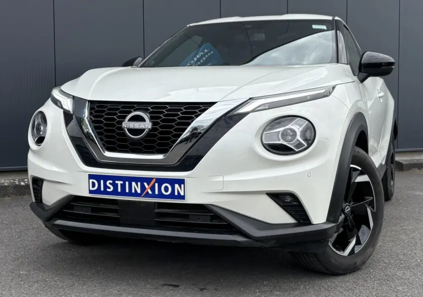 Nissan Juke blanc perle en 3/4 avant droit, avec calandre noire et jantes alliage noires distinctives.