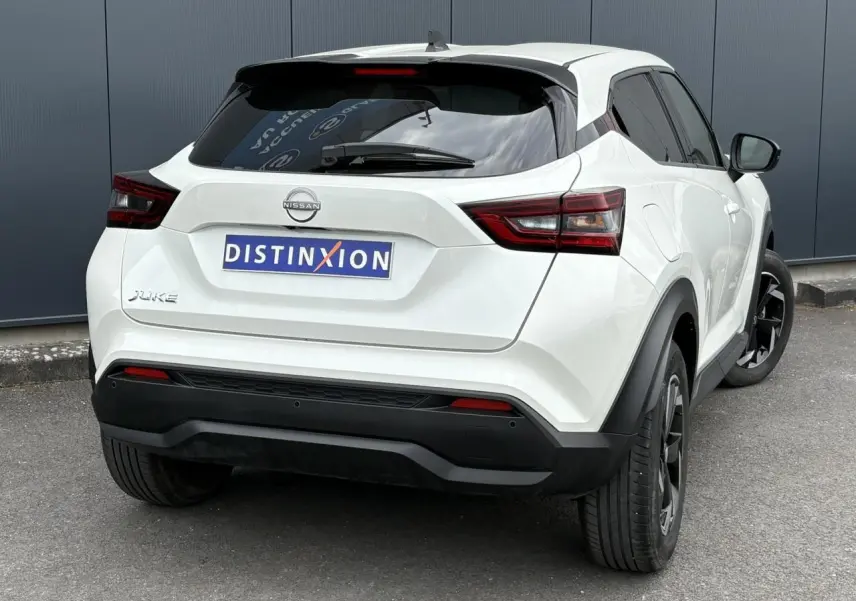 Vue 3/4 arrière droite du Nissan Juke blanc perle 2024 avec jantes alliage noires et vitres teintées.
