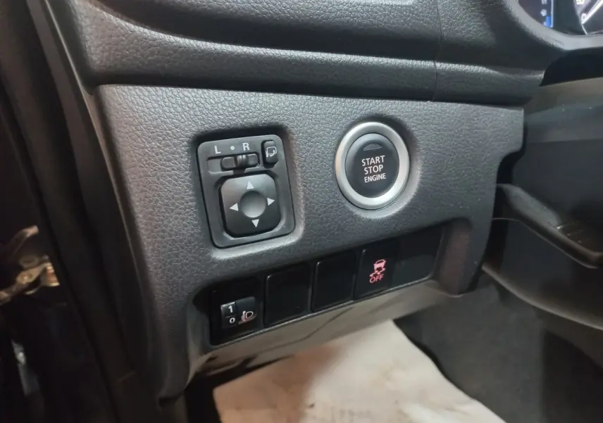 Vue rapprochée côté gauche du tableau de bord gris foncé du Mitsubishi L200 avec bouton Start/Stop et commandes des rétroviseurs.