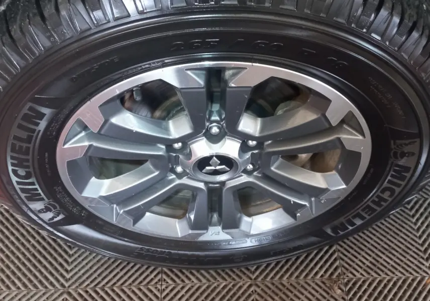 Gros plan sur la jante aluminium grise et le pneu Michelin du Mitsubishi L200 gris foncé, version 2020.