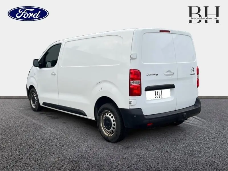 Vue 3/4 arrière droite du Citroën Jumpy blanc Banquise avec attelage et portes arrière fermées.