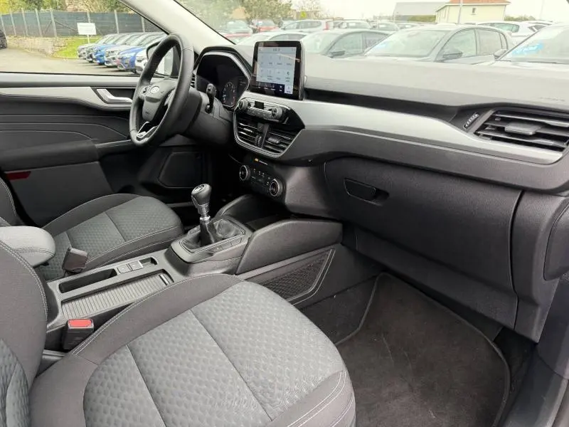 Vue intérieure côté conducteur du Ford Kuga 2024, montrant la console centrale avec boîte manuelle et écran tactile.