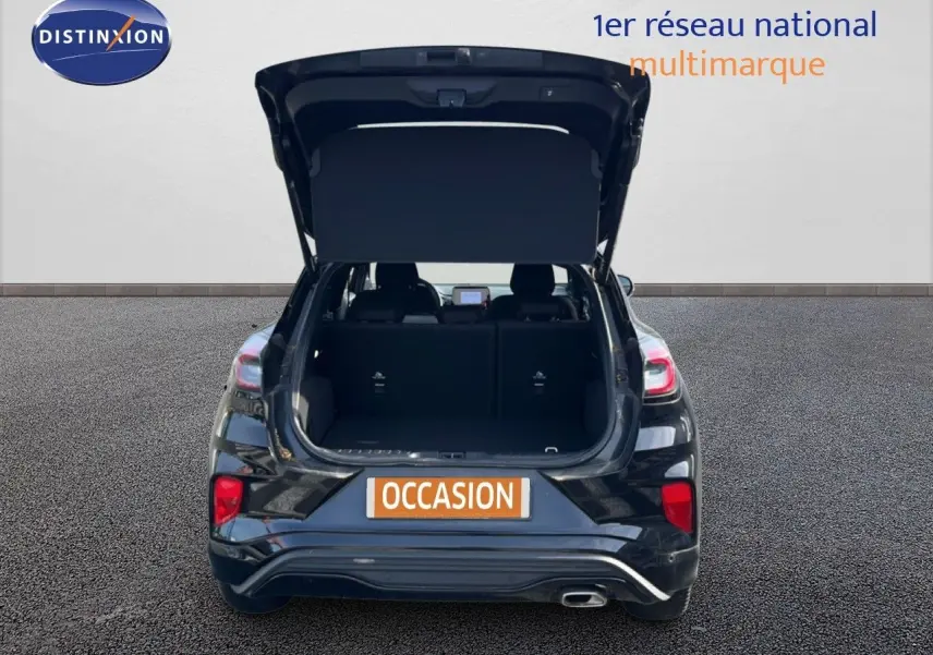 Vue arrière d'un Ford Puma noir Agate Metal 2023 avec hayon ouvert et coffre visible, en extérieur sur sol gris.
