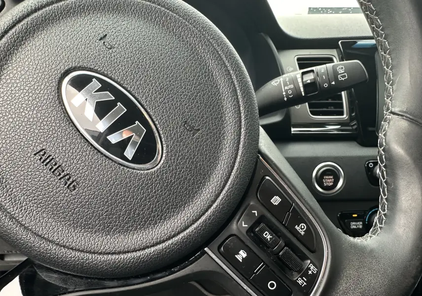 Gros plan sur le volant noir de la Kia Niro hybride rechargeable 2020 avec commandes intégrées et bouton start/stop visible.
