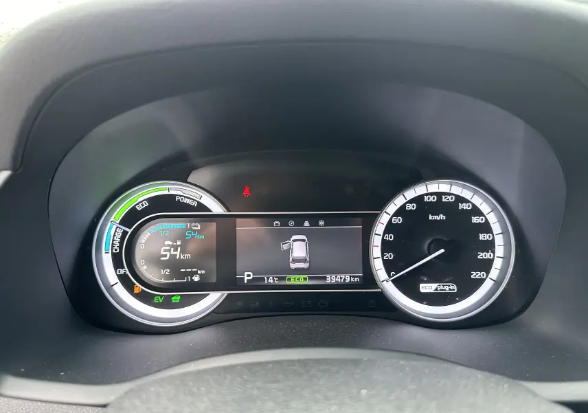 Tableau de bord du Kia Niro hybride rechargeable blanc céleste, affichant la vitesse, autonomie électrique et indicateurs de conduite.