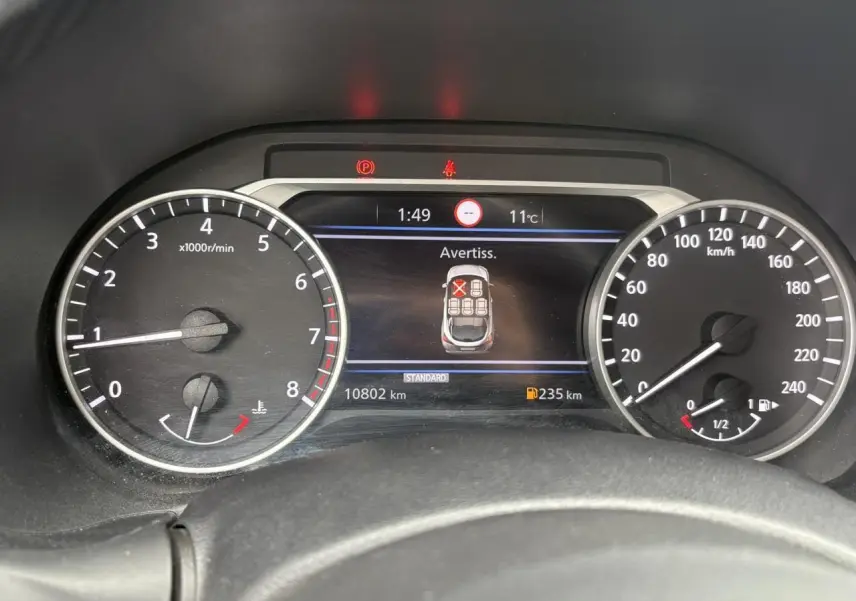 Vue rapprochée du tableau de bord du Nissan Juke blanc perle 2023, affichant les compteurs et l'écran digital.