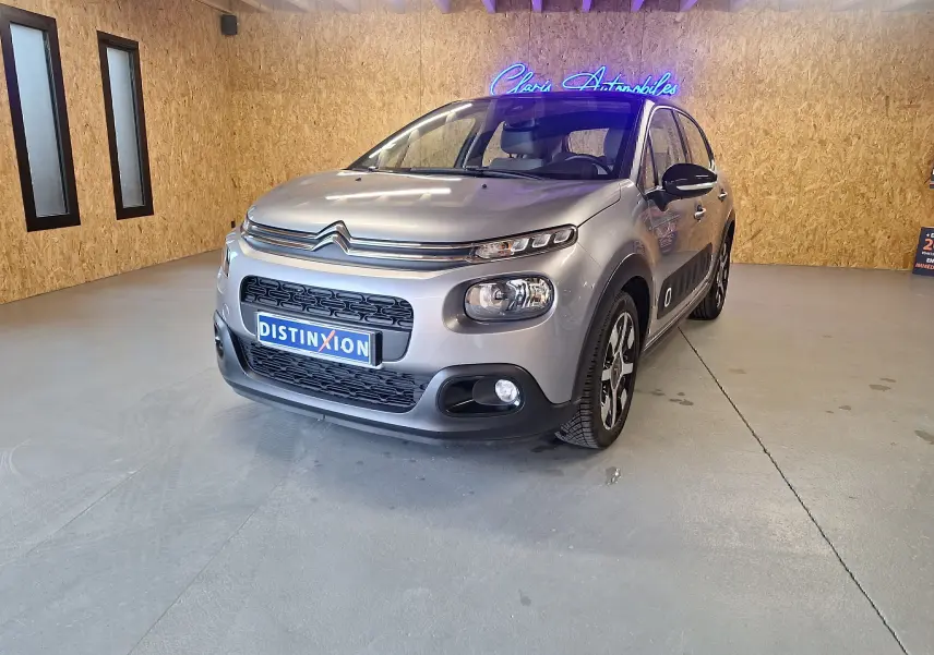 Citroën C3 gris en 3/4 avant droit dans un showroom avec jantes alu et rétroviseurs noirs brillants.