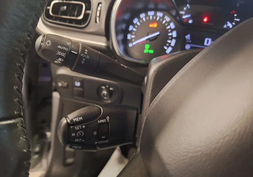 Gros plan sur le volant cuir et les commandes de régulateur de vitesse du tableau de bord d'une Citroën C3 gris 2019.
