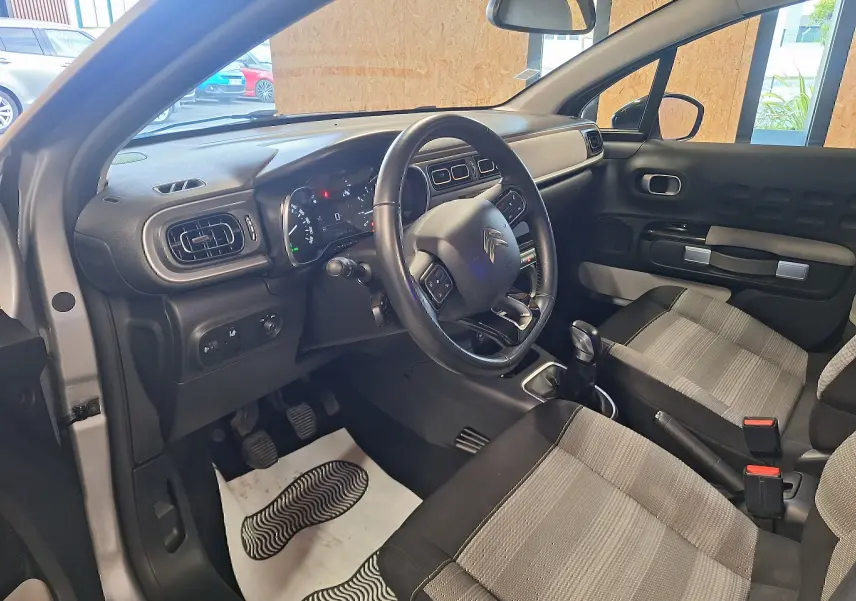 Intérieur avant droit d'une Citroën C3 gris 2019, volant cuir, tableau de bord avec écran tactile et sièges tissu Mica Grey.