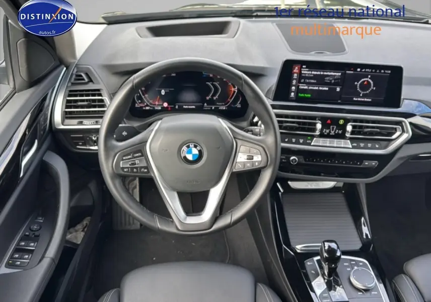 Vue intérieure centrée sur le volant cuir multifonction et tableau de bord numérique du BMW X3 noir 2024