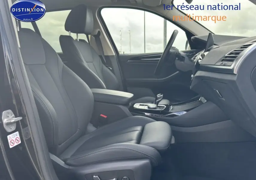 Intérieur noir de la BMW X3 2024 vu côté gauche, avec sièges sport en similicuir et console centrale moderne.