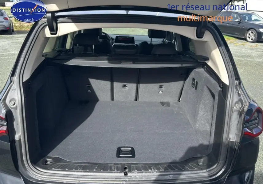 Coffre ouvert d’un BMW X3 noir (2024) vu de l’arrière, montrant l’espace de chargement et la tablette cache-bagages.