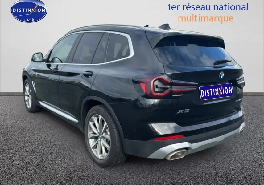 Vue 3/4 arrière droite d'un BMW X3 noir 2024 avec jantes alu et échappement double chromé.