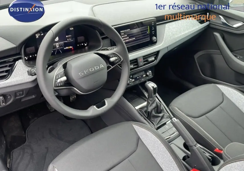 Vue intérieure du tableau de bord et des sièges avant gris noir du Skoda Kamiq 2025 avec volant multifonction et écran tactile central.