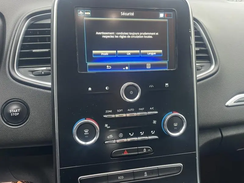 Vue rapprochée de la console centrale noire du Renault Grand Scenic 2022 avec écran tactile affichant un message de sécurité.