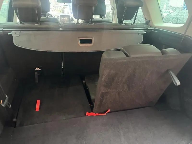Vue arrière du coffre du Renault Grand Scenic bleu Cosmos 2022 avec siège arrière partiellement rabattu et cache-bagages déployé.