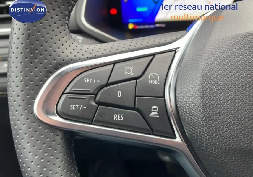 Gros plan sur les commandes au volant perforé d'une Renault Symbioz bleu Iron Metal, avec affichage numérique en arrière-plan.