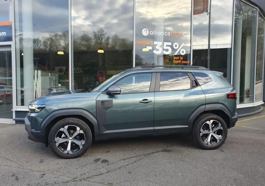 Profil droit du Dacia Duster 2026 vert cèdre avec jantes alliage 18” diamantées et barres de toit longitudinales.