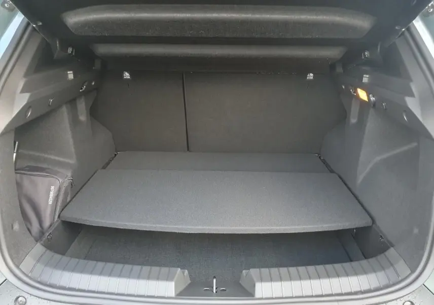 Coffre ouvert du Dacia Duster 2026, vue arrière, montrant la tablette de séparation et l'intérieur noir du coffre.