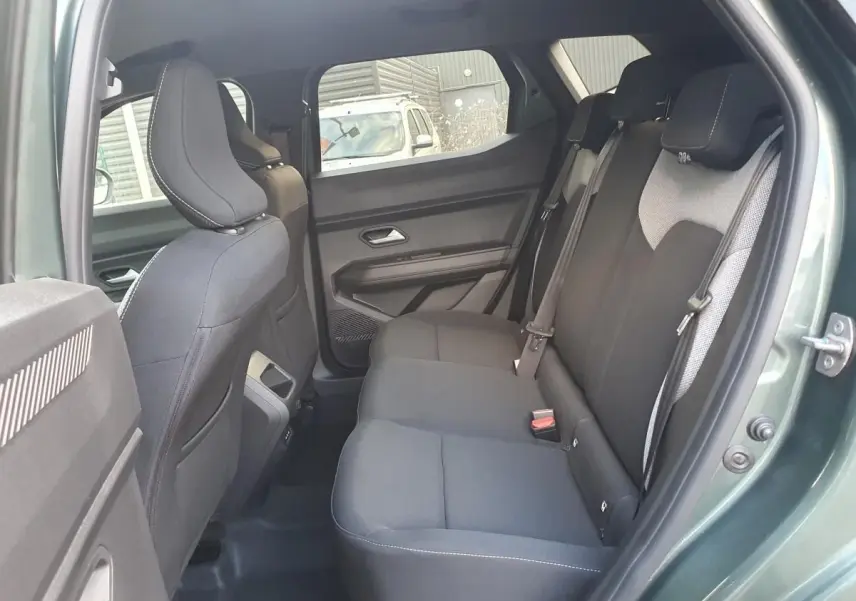 Vue intérieure côté droit de la banquette arrière noire du Dacia Duster vert cèdre avec prises USB à l'arrière de la console.