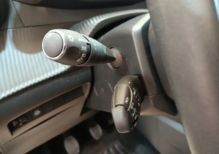 Gros plan sur les commandes au volant d’une Peugeot 208 PureTech 100 S&S Allure Business, intérieur noir.