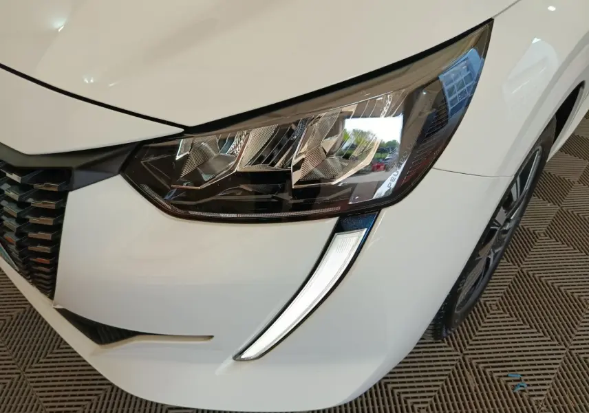 Gros plan sur le phare avant droit blanc de la Peugeot 208 PureTech 100 S&S Allure Business 2021.
