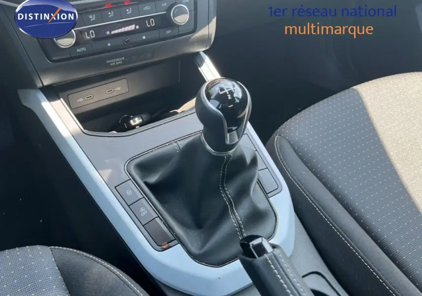 Gros plan sur la console centrale de la SEAT Arona 2025, mettant en valeur le levier de vitesses manuel et les sièges en tissu gris.