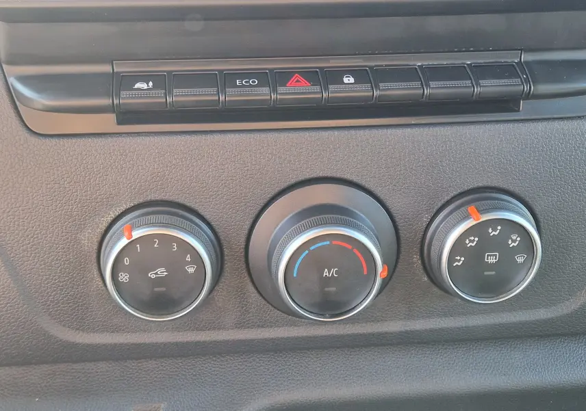 Gros plan sur les commandes de climatisation et boutons de fonction du tableau de bord du Renault Master blanc.