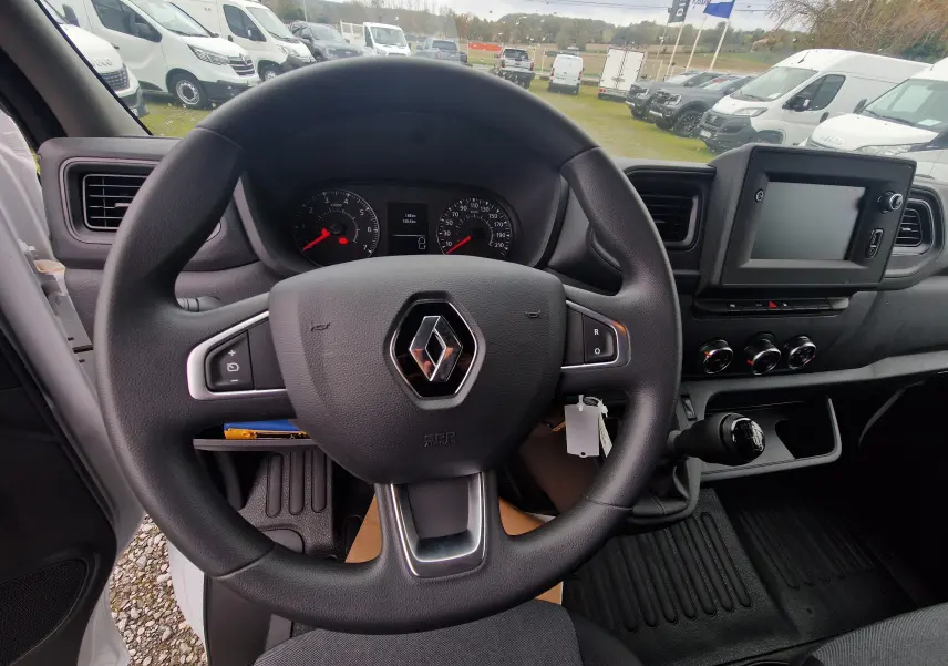 Vue intérieure centrée sur le volant Renault d'un Master blanc 2023, avec tableau de bord et écran tactile visibles.