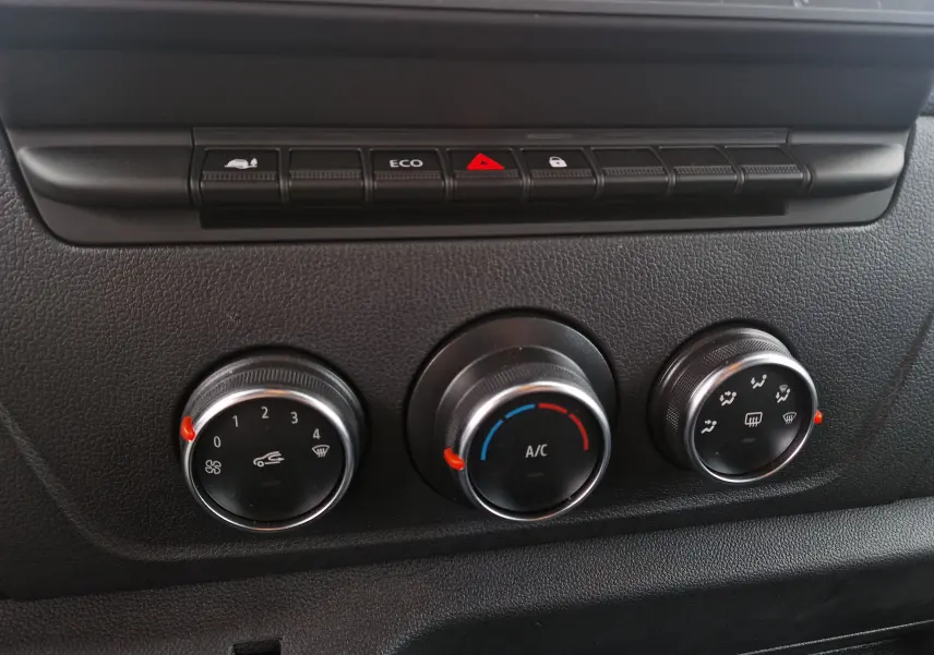Gros plan sur les commandes de climatisation noires du tableau de bord du Renault Master blanc 2023.