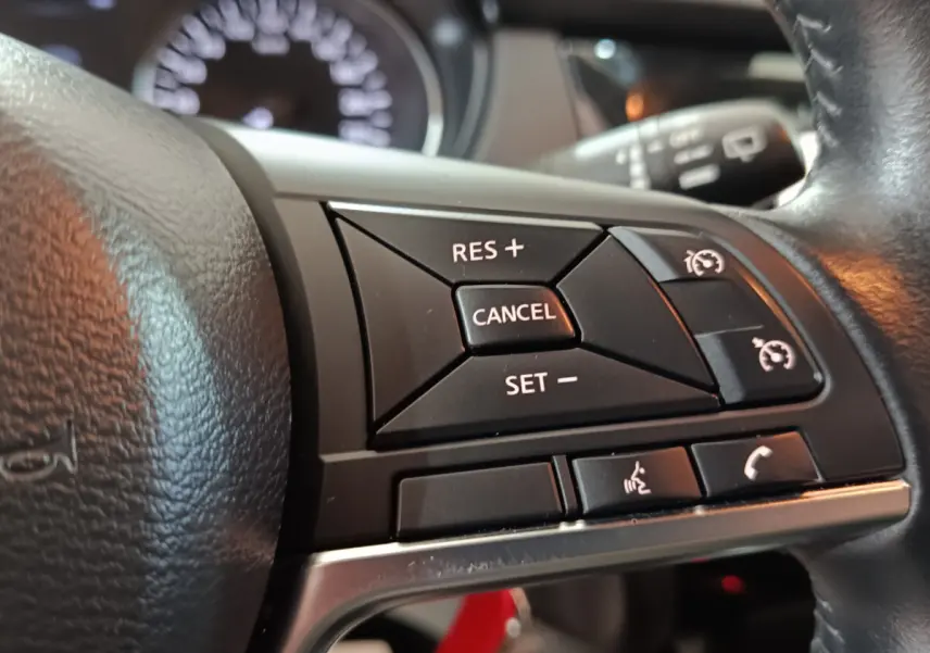 Gros plan sur les commandes de régulateur de vitesse et téléphone au volant cuir du Nissan Qashqai 2019.