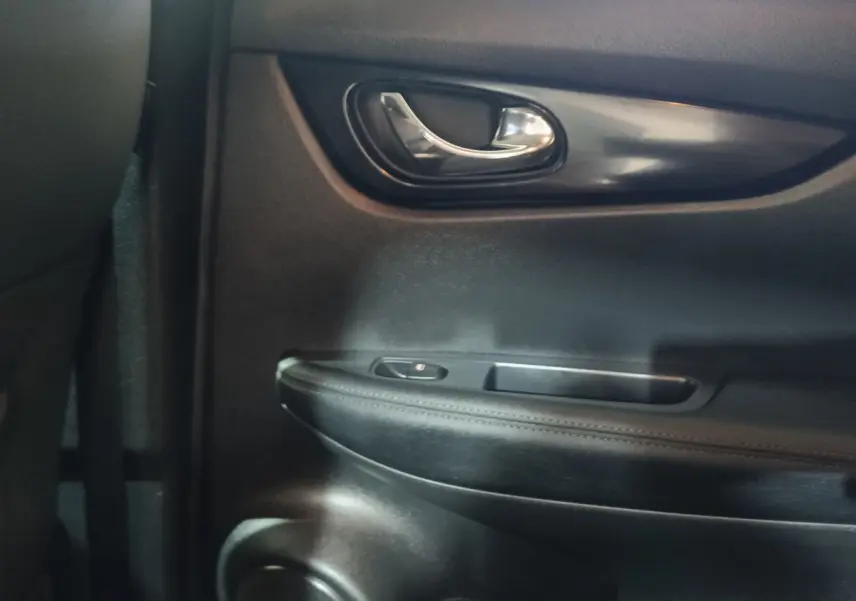 Détail de la porte intérieure côté droit du Nissan Qashqai 1.5 DCI 115 Business Edition, avec poignée chrome et accoudoir noir.