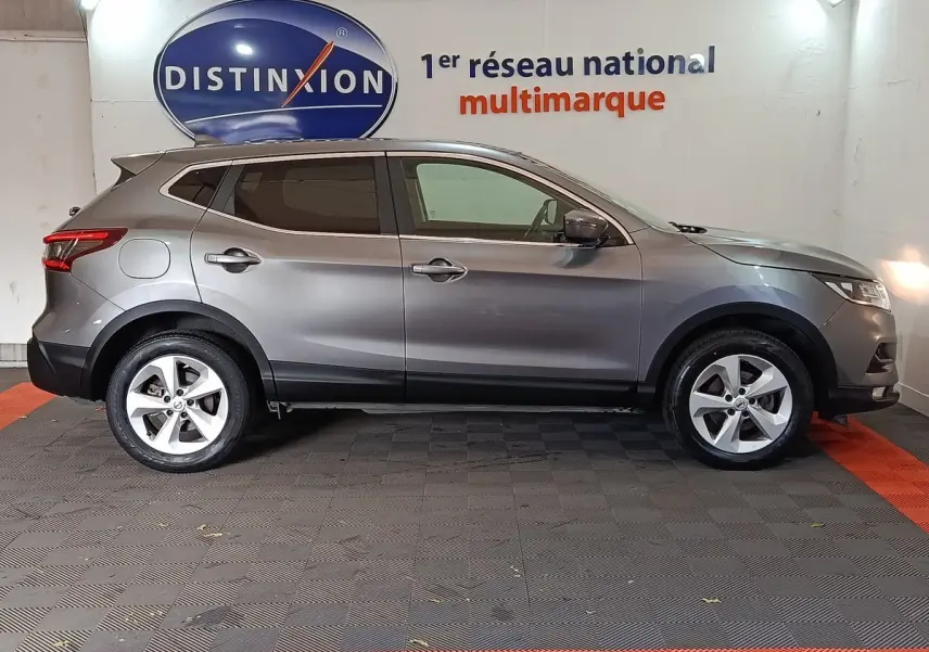 Vue de profil côté gauche d'un Nissan Qashqai gris clair 2019 garé en intérieur sur sol carrelé.