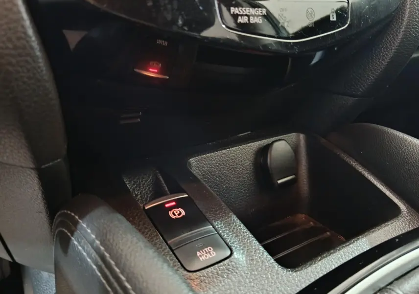Gros plan sur la console centrale noire du Nissan Qashqai 2019, montrant frein à main électrique et prise 12V.