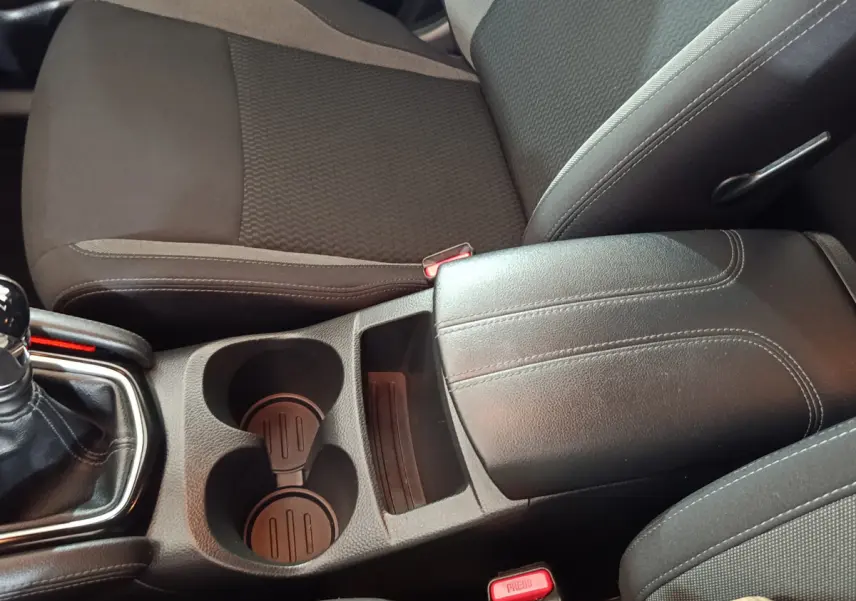 Vue rapprochée de la console centrale noire et des sièges tissu gris foncé du Nissan Qashqai 1.5 DCI 115 Business Edition 2019.