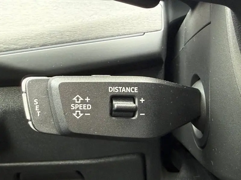 Gros plan sur la commande de régulateur de vitesse du volant d’un Audi Q3 2.0 TDI 150ch S line noir métallisé 2026.