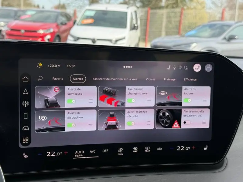 Vue intérieure du tableau de bord numérique de l'Audi Q3 2026, affichant les alertes d'aide à la conduite.