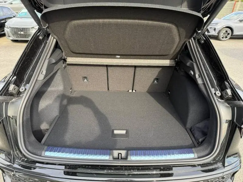 Coffre ouvert vu de l'arrière d'un Audi Q3 2026 noir Mythique métallisé, montrant un espace de chargement spacieux et propre.