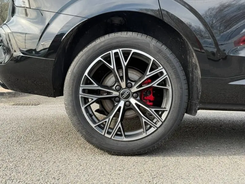 Gros plan sur la roue arrière droite d’un Audi Q3 2026 noir métallisé avec étrier de frein rouge et jante alliage sportive.