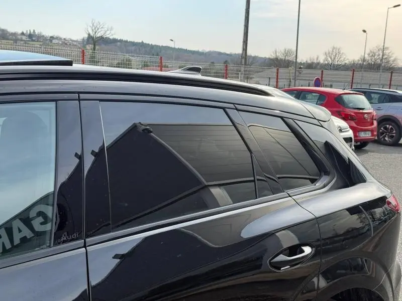 Vue latérale gauche du toit et des vitres teintées d'un Audi Q3 2026 noir Mythique métallisé avec barres de toit.