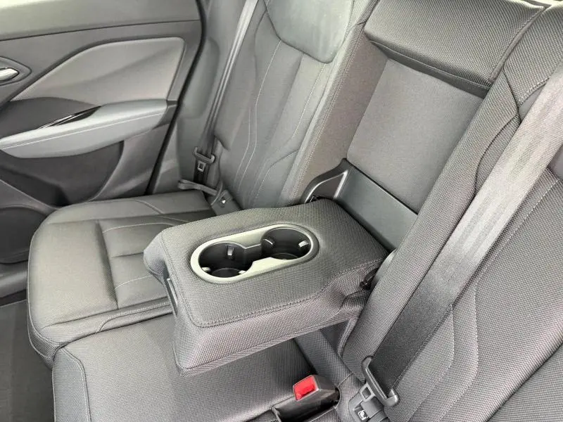 Vue intérieure du siège arrière droit de l'Audi Q3 2026, tissu gris avec accoudoir central et porte-gobelets intégrés.