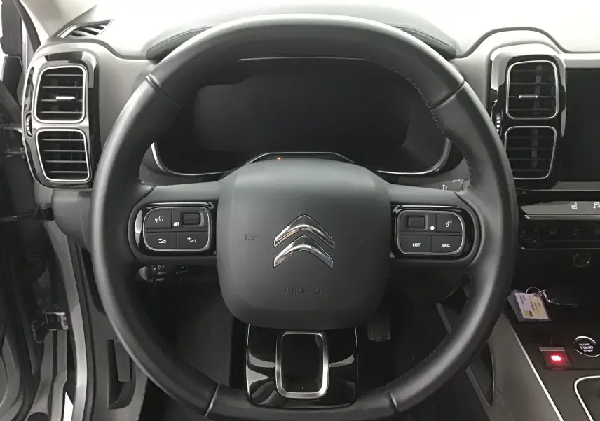 Vue centrée sur le volant en cuir noir du Citroën C5 Aircross gris, avec commandes intégrées et tableau de bord numérique.
