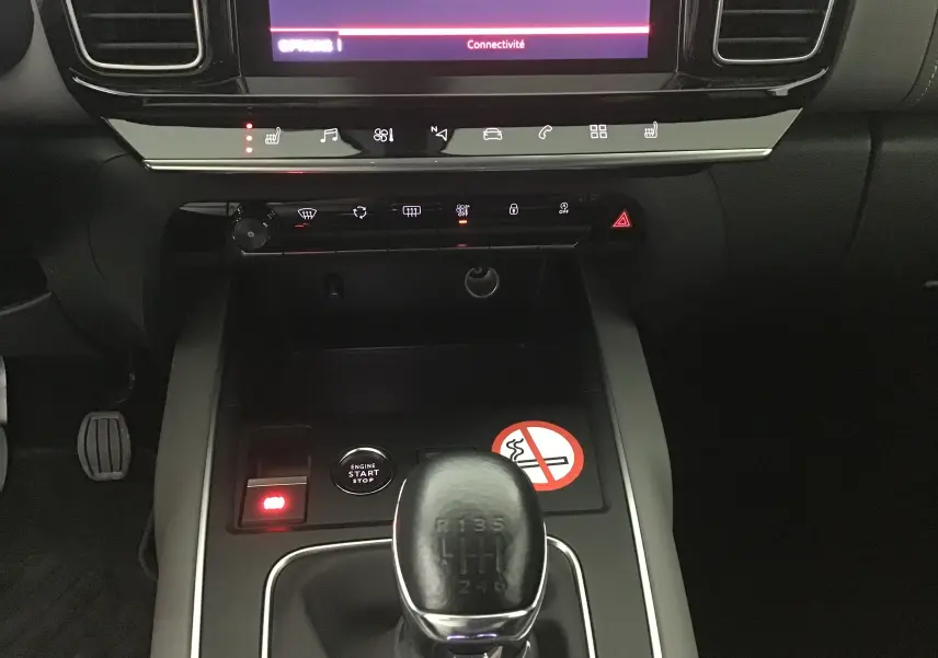 Vue rapprochée de la console centrale du Citroën C5 Aircross gris, avec levier de vitesse manuel et écran tactile allumé.