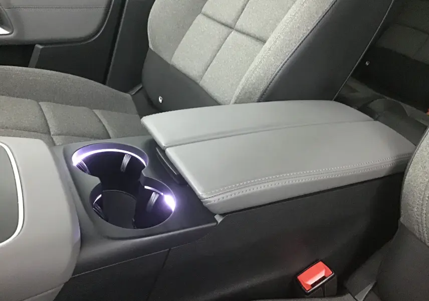 Gros plan sur la console centrale avec accoudoir gris et porte-gobelets éclairés du Citroën C5 Aircross 2021 intérieur tissu gris.