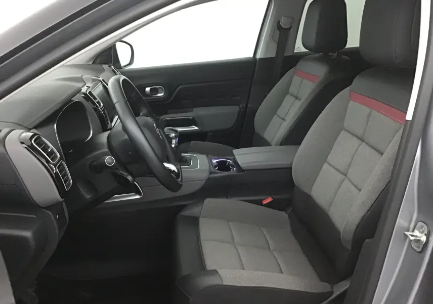 Intérieur avant droit du Citroën C5 Aircross gris Artense 2021, sièges tissu gris avec bande rouge et volant cuir.