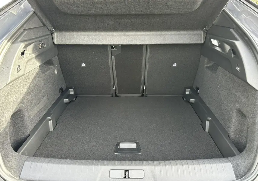 Coffre ouvert vu de l'arrière du Peugeot 3008 Hybrid gris Artense, espace de chargement vide et tapis noir.