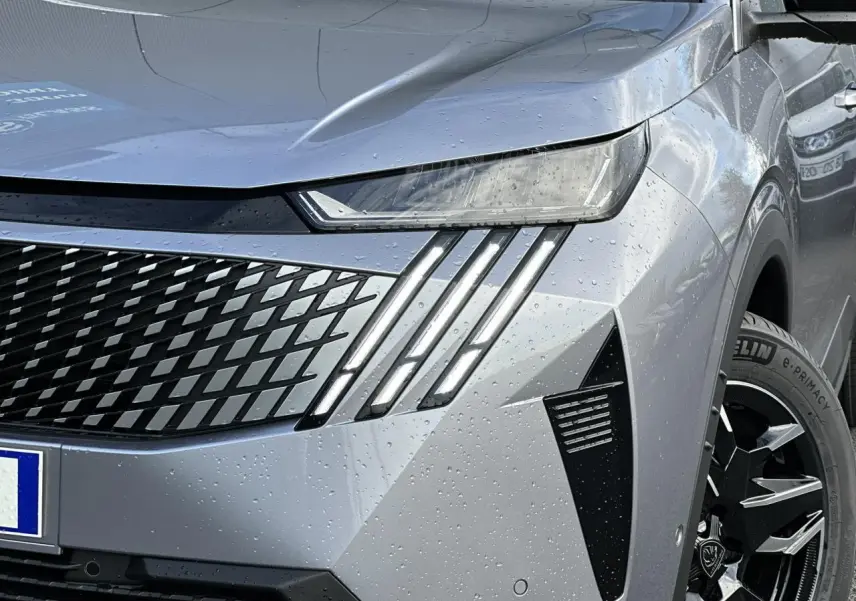 Gros plan sur l'avant droit gris Artense du Peugeot 3008 Hybrid 2025 avec feux LED griffés et jante alliage noire.