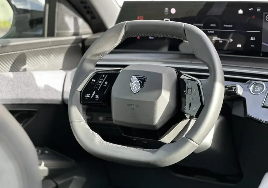 Gros plan sur le volant cuir gris du Peugeot 3008 Hybrid 2025 avec tableau de bord numérique panoramique.